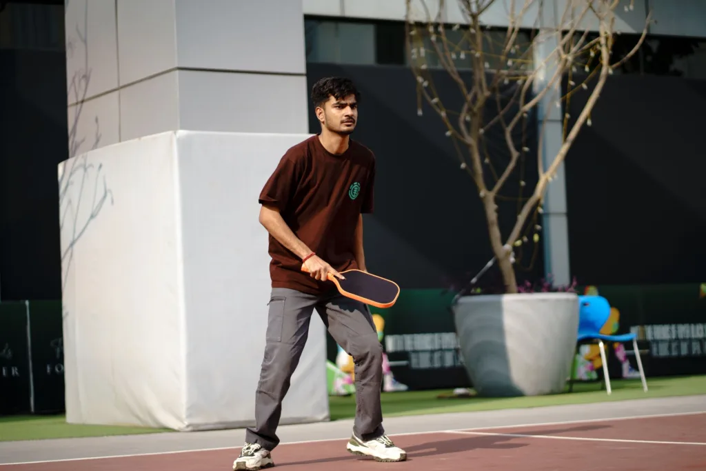 Player holding a paddle, ready to play on an outdoor pickleball court