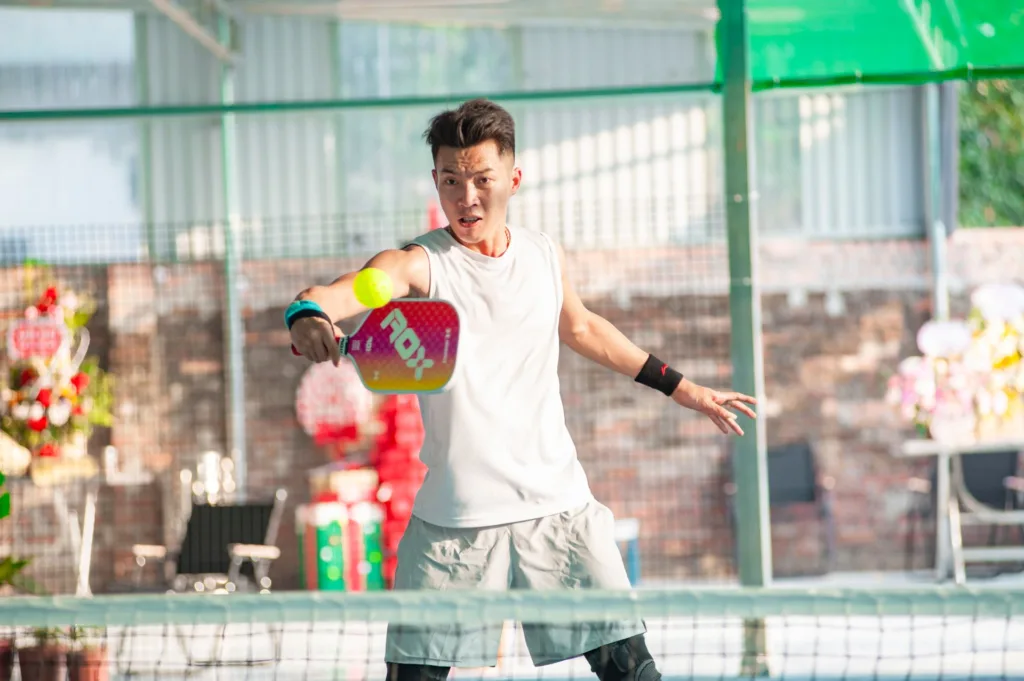 Player lunging for a low ball on an indoor pickleball court